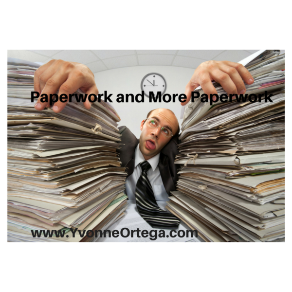 Man at desk with paperwork stacked on either side of him